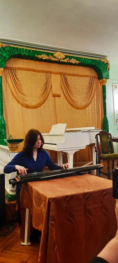 Нина Старостина в синем платье исполняет  музыкальные произведения  на вечере «МОСКВА – ГАВАНА – ПЕКИН»